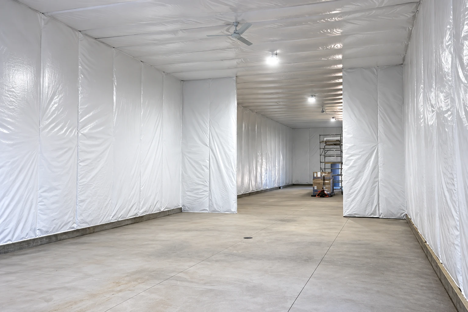 A large empty commercial room has white insulated wall and ceiling coverings and a concrete floor.